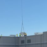Helicopter placing rooftop HVAC unit during commercial HVAC installation